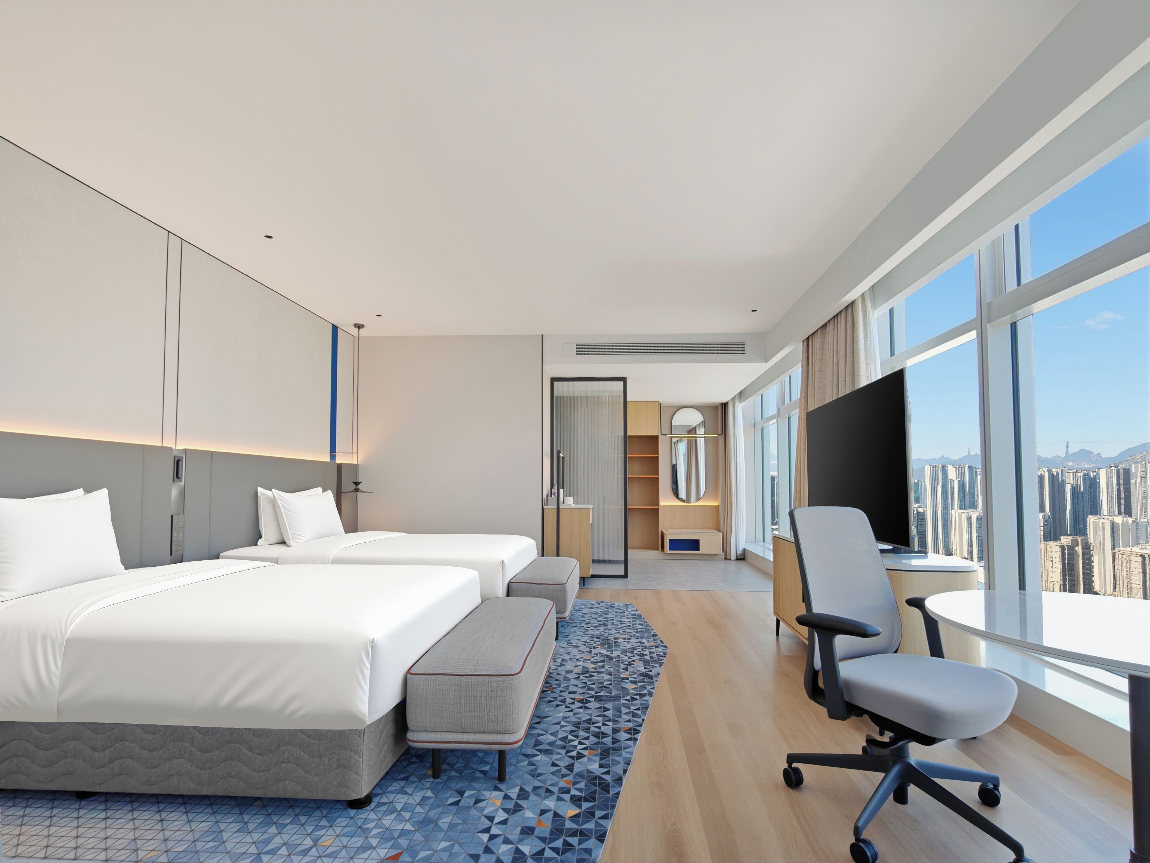 Habitación de hotel moderna con dos camas, un escritorio y vistas a la ciudad.