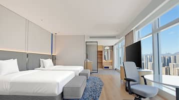 Habitación de hotel moderna con dos camas, un escritorio y vistas a la ciudad.