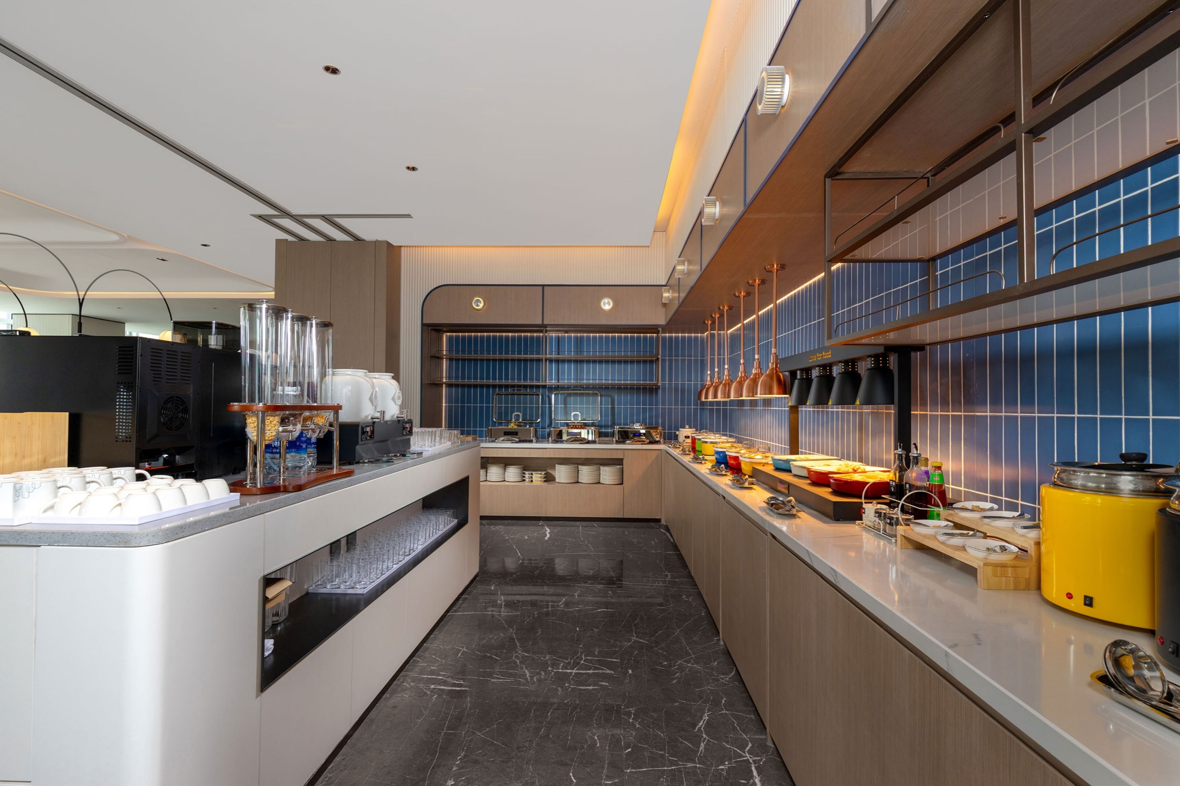 Una cocina moderna con piso de mármol, estación de café y zona de bufé.