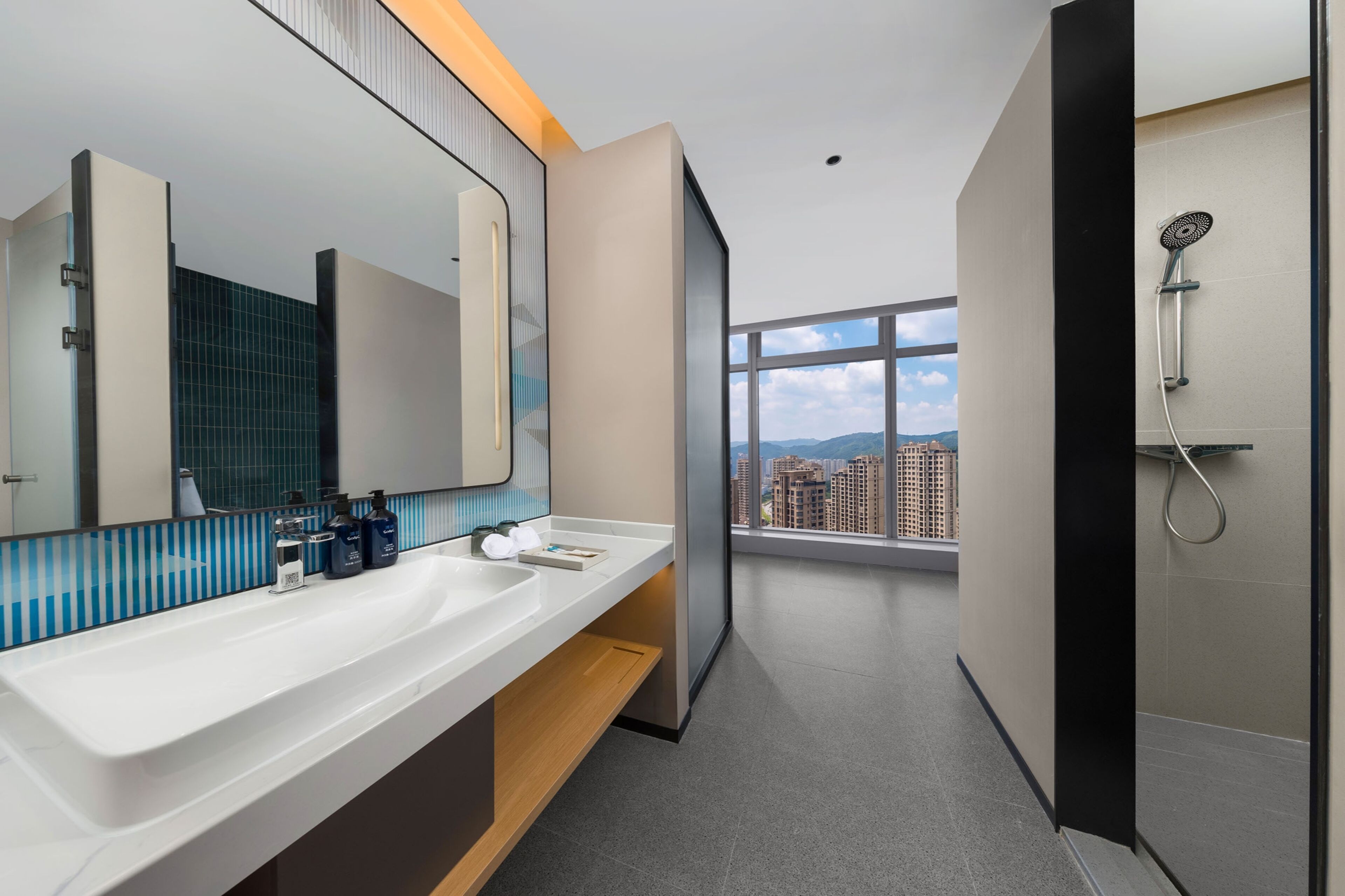 A modern bathroom with a dual sink vanity, a large mirror, and a shower.