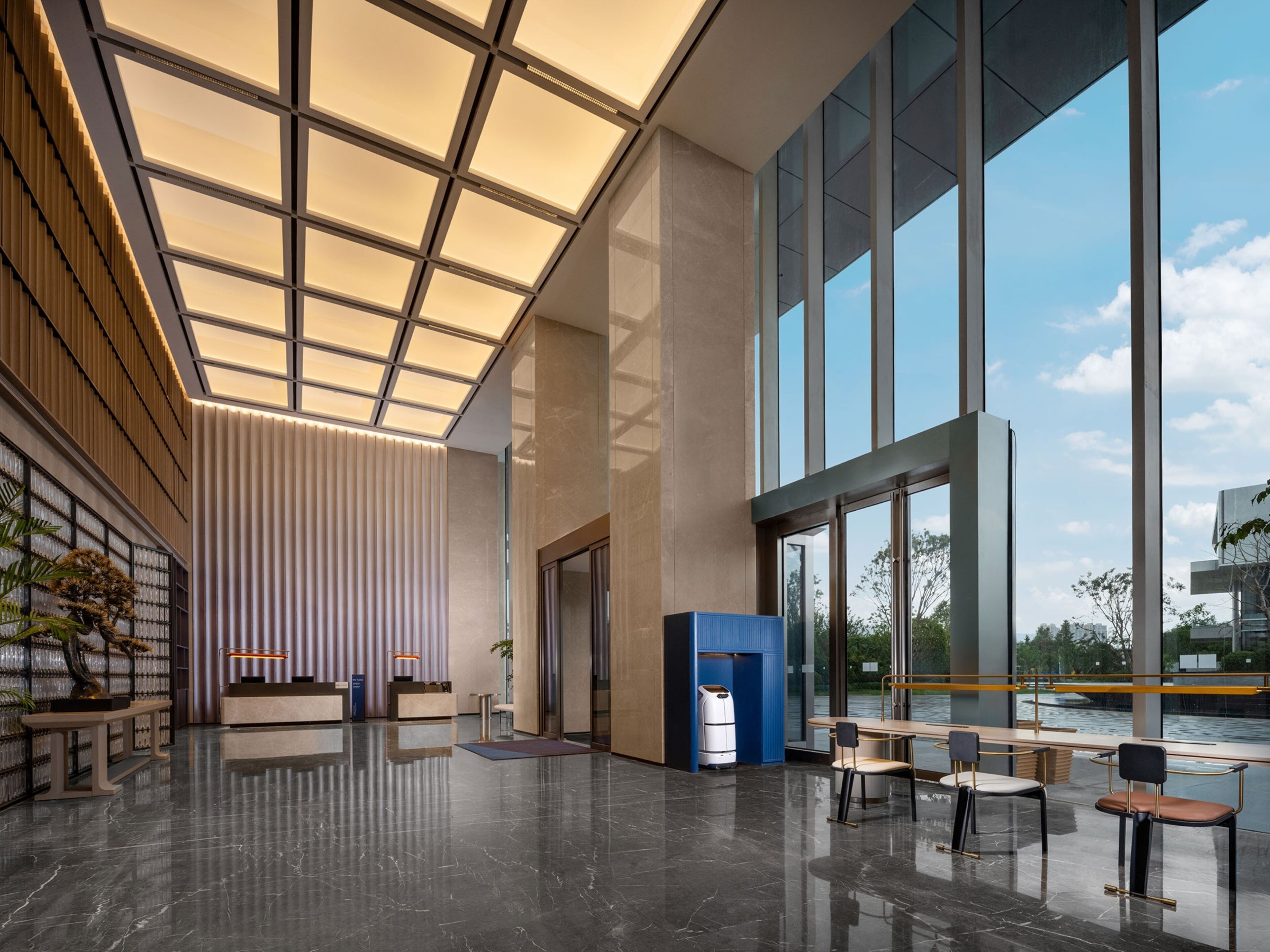 A spacious lobby with a high ceiling, large windows, and a reception desk.