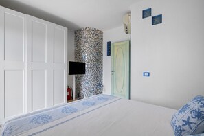 A bedroom with a bed, a wardrobe, a wall-mounted TV, and a door with a unique pattern.