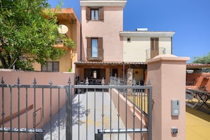 A two-story building with a balcony and a gate. - Villa Aurora Tortolì Holiday Home with Balcony, Wi-Fi, and Air Conditioning (Tortolì)