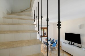 A staircase with a modern design, leading to a dining area with a table and chairs. - Villa Aurora Tortolì Holiday Home with Balcony, Wi-Fi, and Air Conditioning (Tortolì)