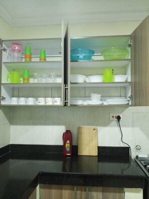 A kitchen with open cabinets containing various dishes and utensils. - Sun-Drenched Coastal Retreat in Vibrant Mombasa (Mombasa)