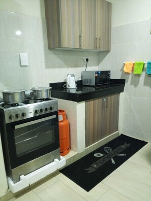 A kitchen with a stove, oven, microwave, and a gas cylinder. - Sun-Drenched Coastal Retreat in Vibrant Mombasa (Mombasa)