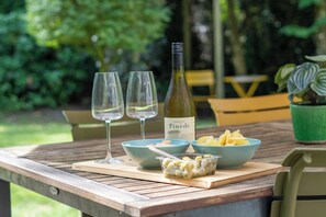 A wooden table with two wine glasses, a bottle of wine, and bowls of food. - Moss & Leaf Lodge op de Veluwe in Lunteren (Lunteren)