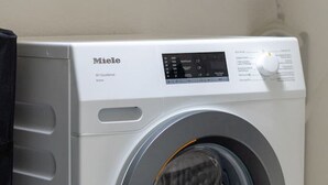 Miele-merkkinen pyykinpesukone, jossa on etupuolelta täytettävä malli, ohjauspaneeli ja läpinäkyvä luukku.