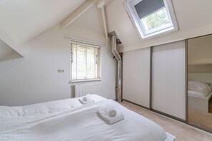 A bedroom with a bed, a window, a radiator, and a wardrobe. - Moss & Leaf Lodge op de Veluwe in Lunteren (Lunteren)