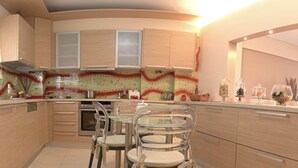 A modern kitchen with wooden cabinets, a glass dining table, and chairs.