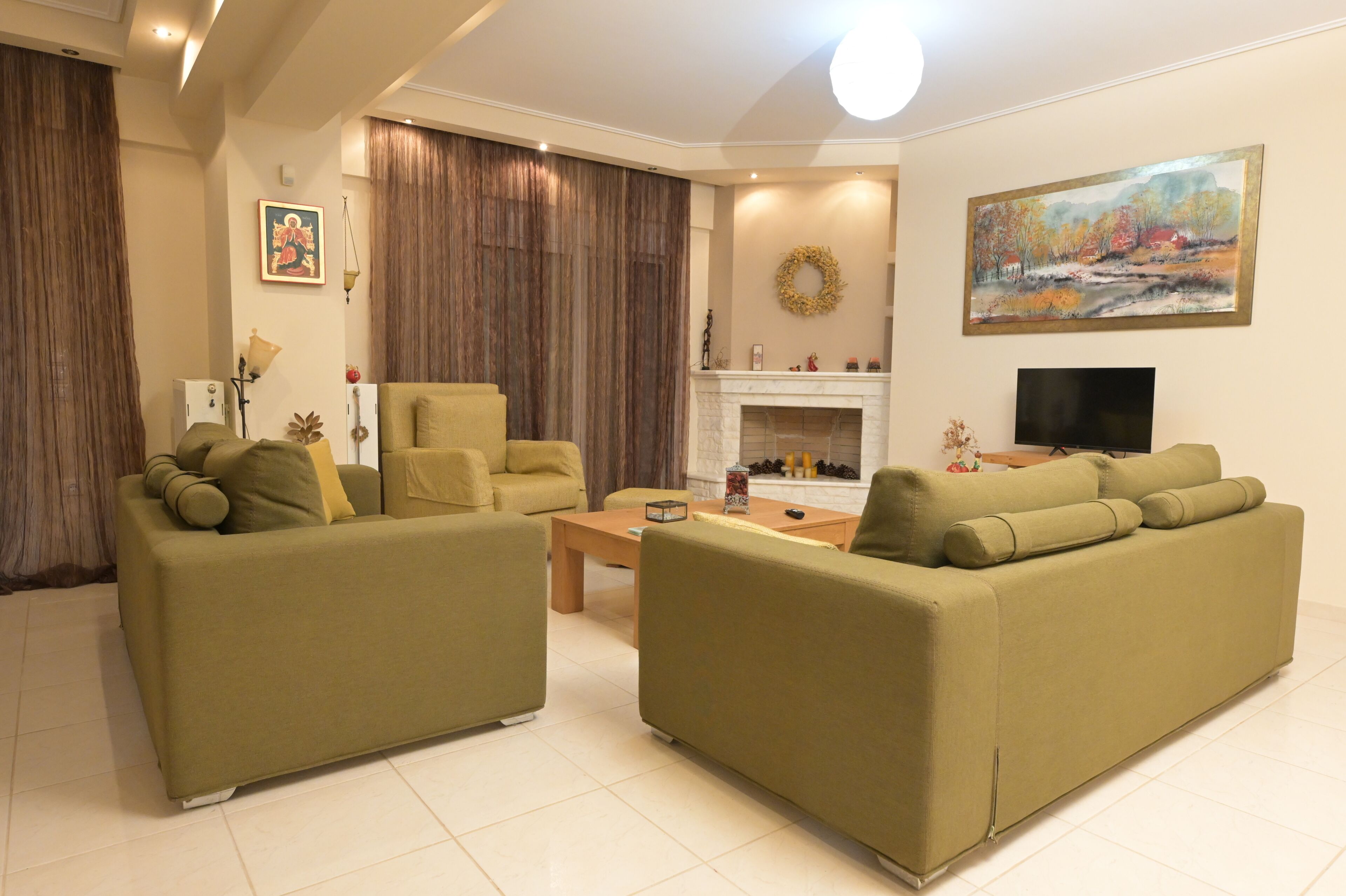A living room with two sofas, a coffee table, a fireplace, a TV, and a painting on the wall.