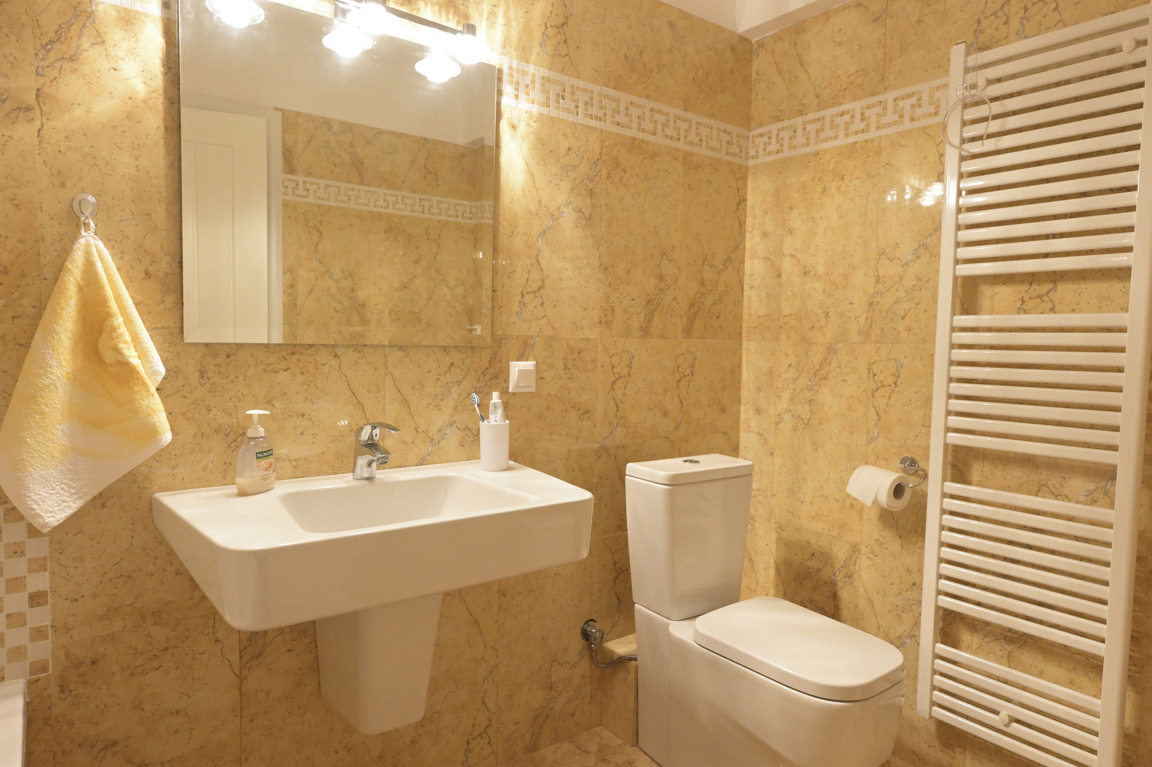 Un baño con lavamanos, inodoro y perchero para toallas.