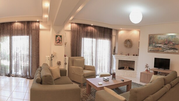 A living room with a fireplace, a television, and a large window with curtains.