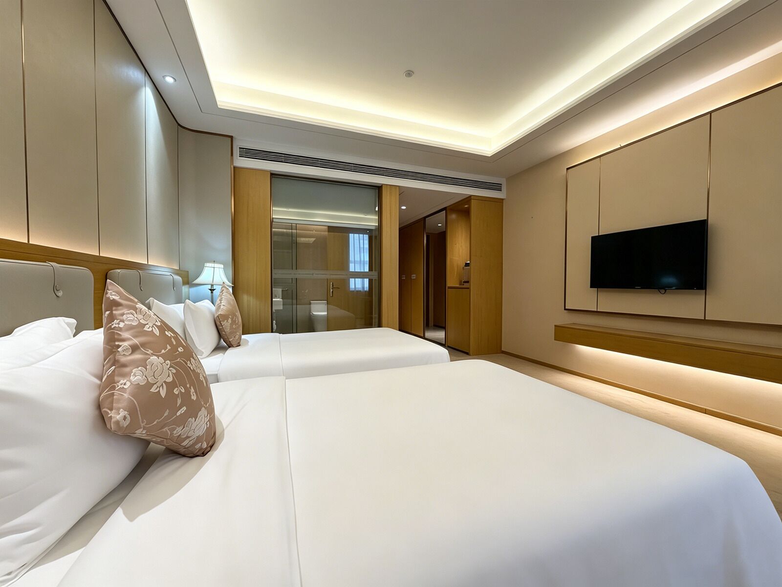 Une chambre d’hôtel avec deux lits, une télévision et un dressing.