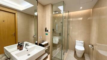 A modern bathroom with a glass shower enclosure, a dual sink vanity, and a toilet.