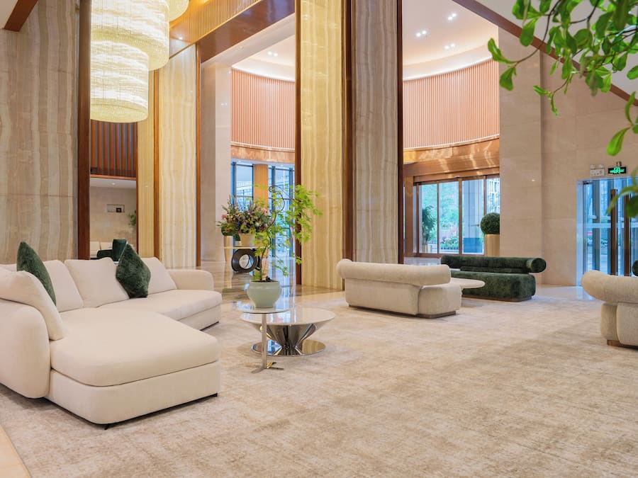 A spacious lobby with a large white sofa, a round coffee table, and a potted plant.