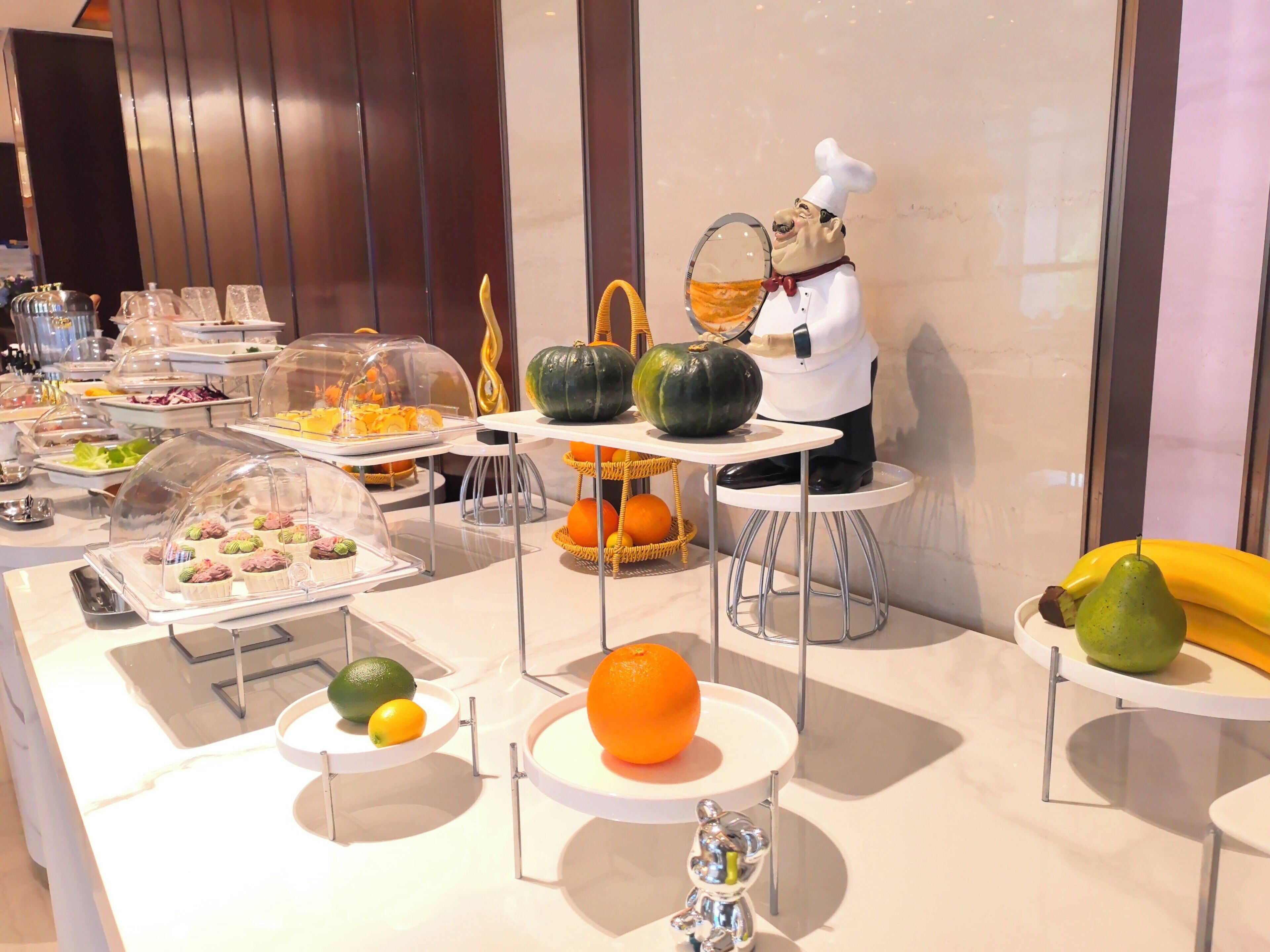 A buffet with various food items and a decorative chef figure.