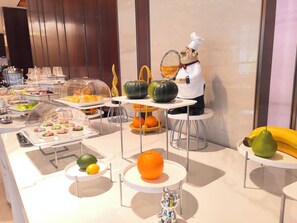 Un bufé con diversos alimentos y una figura decorativa de un chef.