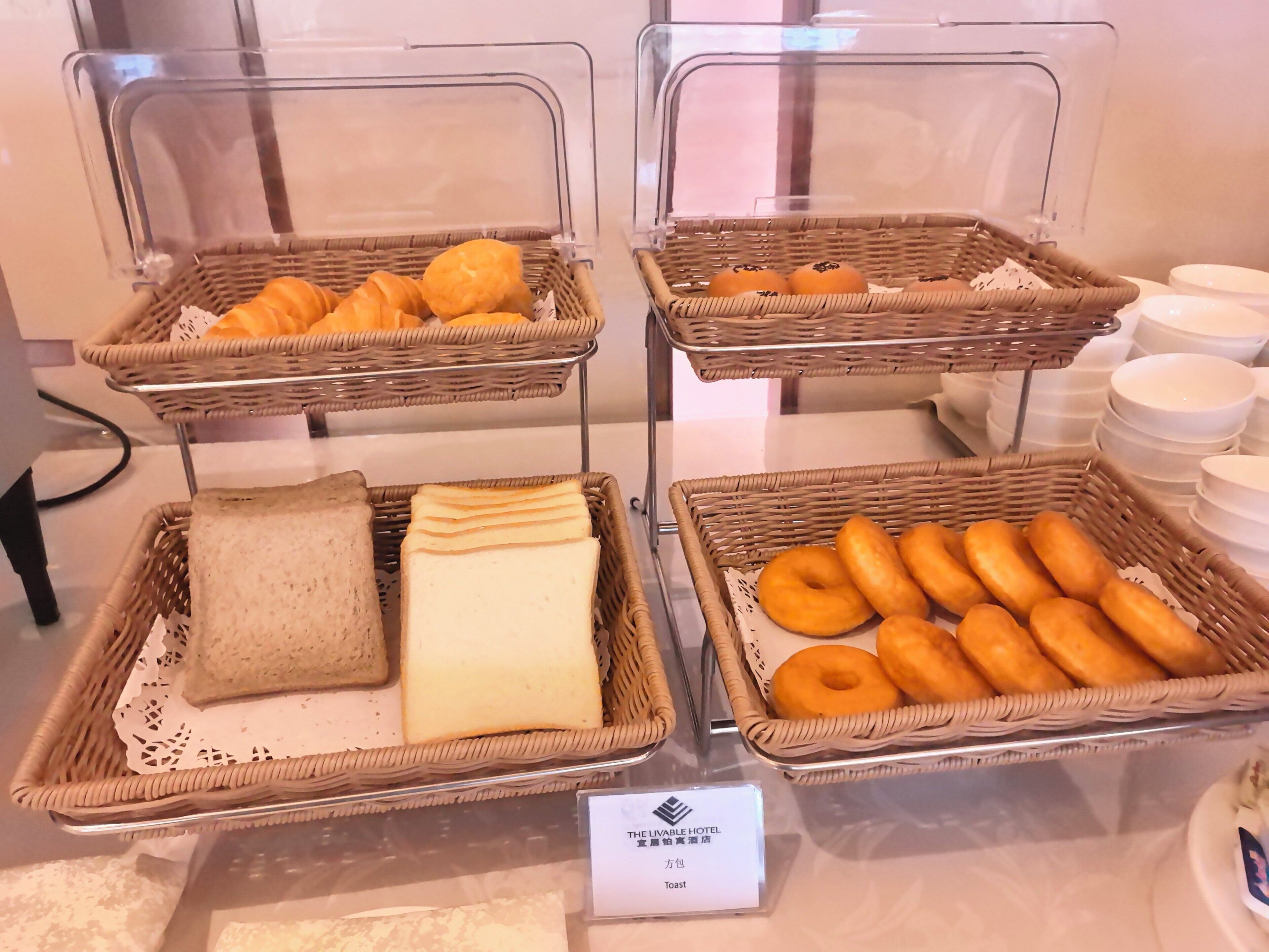 Noutopöytä, jossa on tarjolla monenlaista ruokaa, kuten leipää, leivonnaisia ja donitseja.
