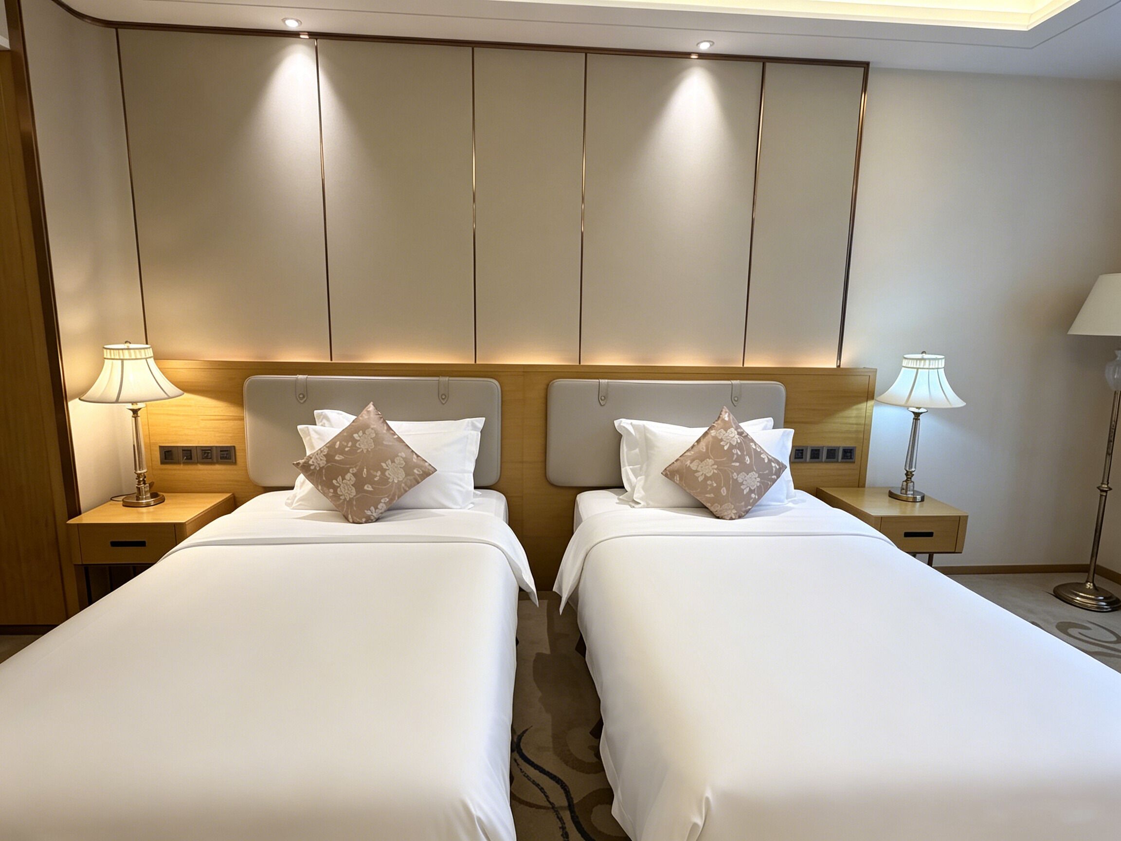 Une chambre d’hôtel avec deux lits, chacun étant équipé d’un oreiller et d’une table de chevet avec une lampe.