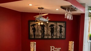 Un espace bar avec un mur rouge, un comptoir en bois et des tabourets de bar noirs.