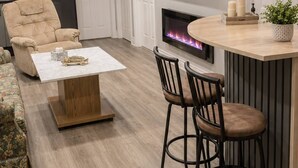 Un salon moderne avec une cheminée, un canapé, une table basse et un téléviseur fixé au mur.