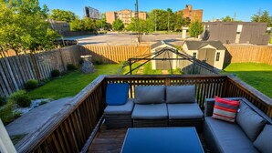 Une terrasse avec des sièges extérieurs, une vue sur un quartier résidentiel et un petit abri de jardin.