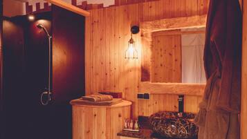 Un baño de madera con lavamanos, espejo, toallero y ducha.