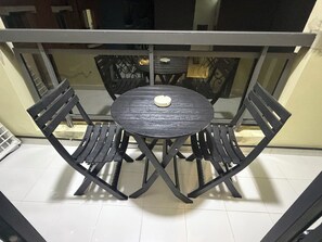 A round table with four chairs, a glass top, and a white object on the table. - STUNNING 2-Bedroom Apartment for Rent. (Dakar)