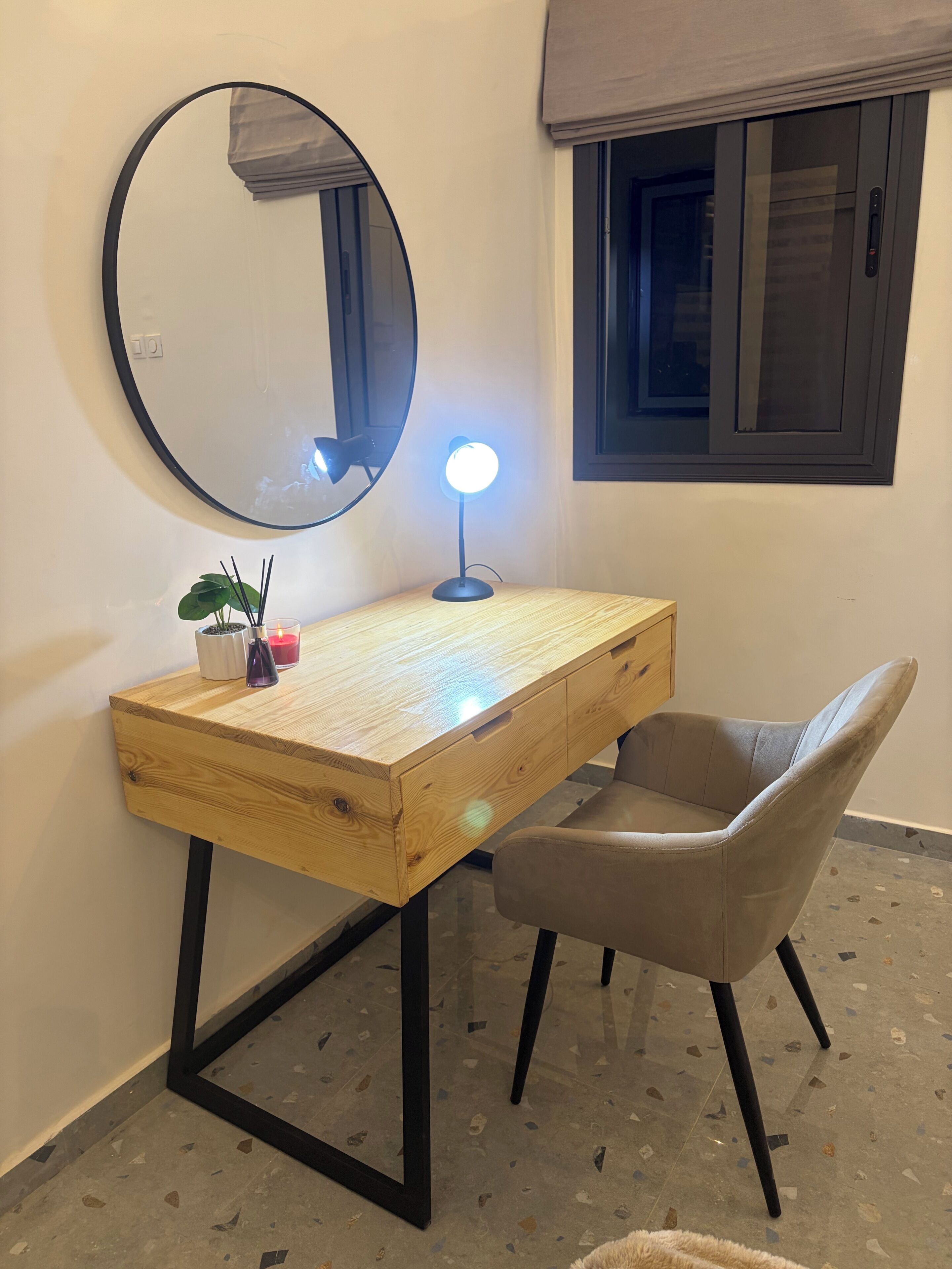 Ein Holztisch mit einem runden Spiegel, einer Schreibtischlampe und einem Stuhl.