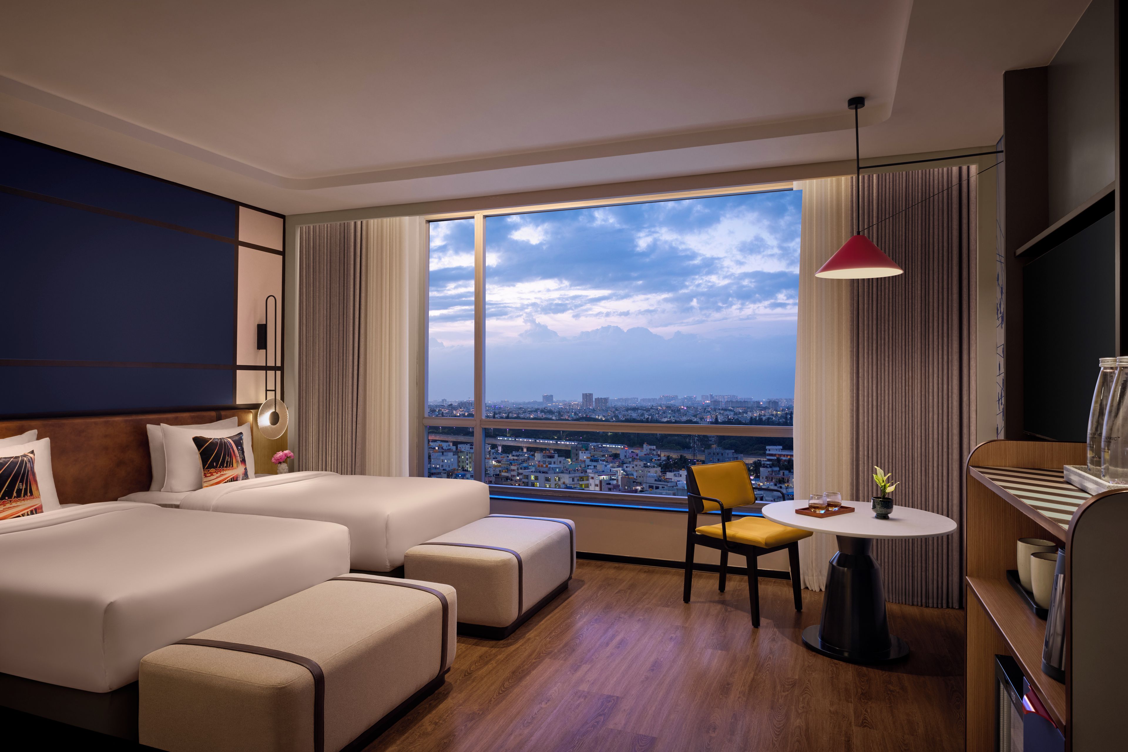 Habitación de hotel con una cama grande, un escritorio, una silla y vistas a la ciudad.