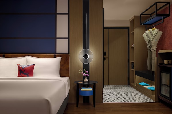 Una habitación de hotel con una cama, mesita de noche y un armario.