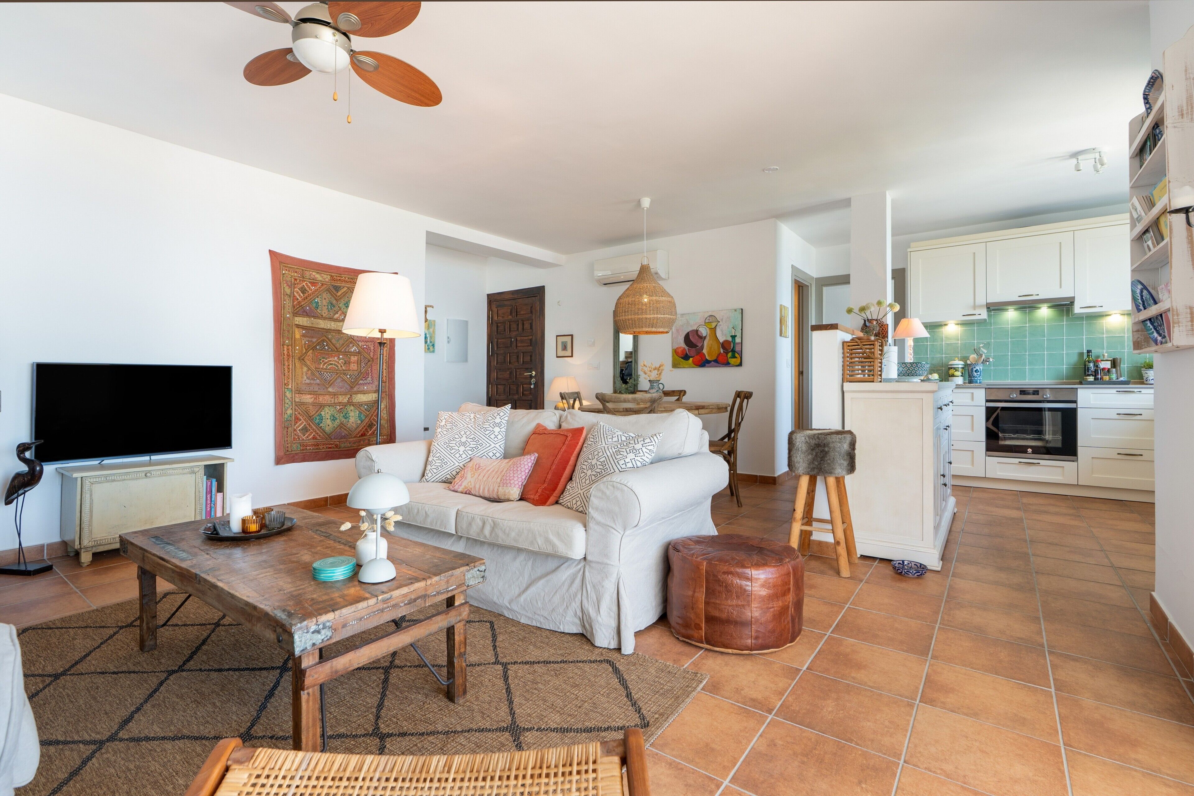Un salon comprenant un canapé, une table basse, un téléviseur et un ventilateur de plafond.
