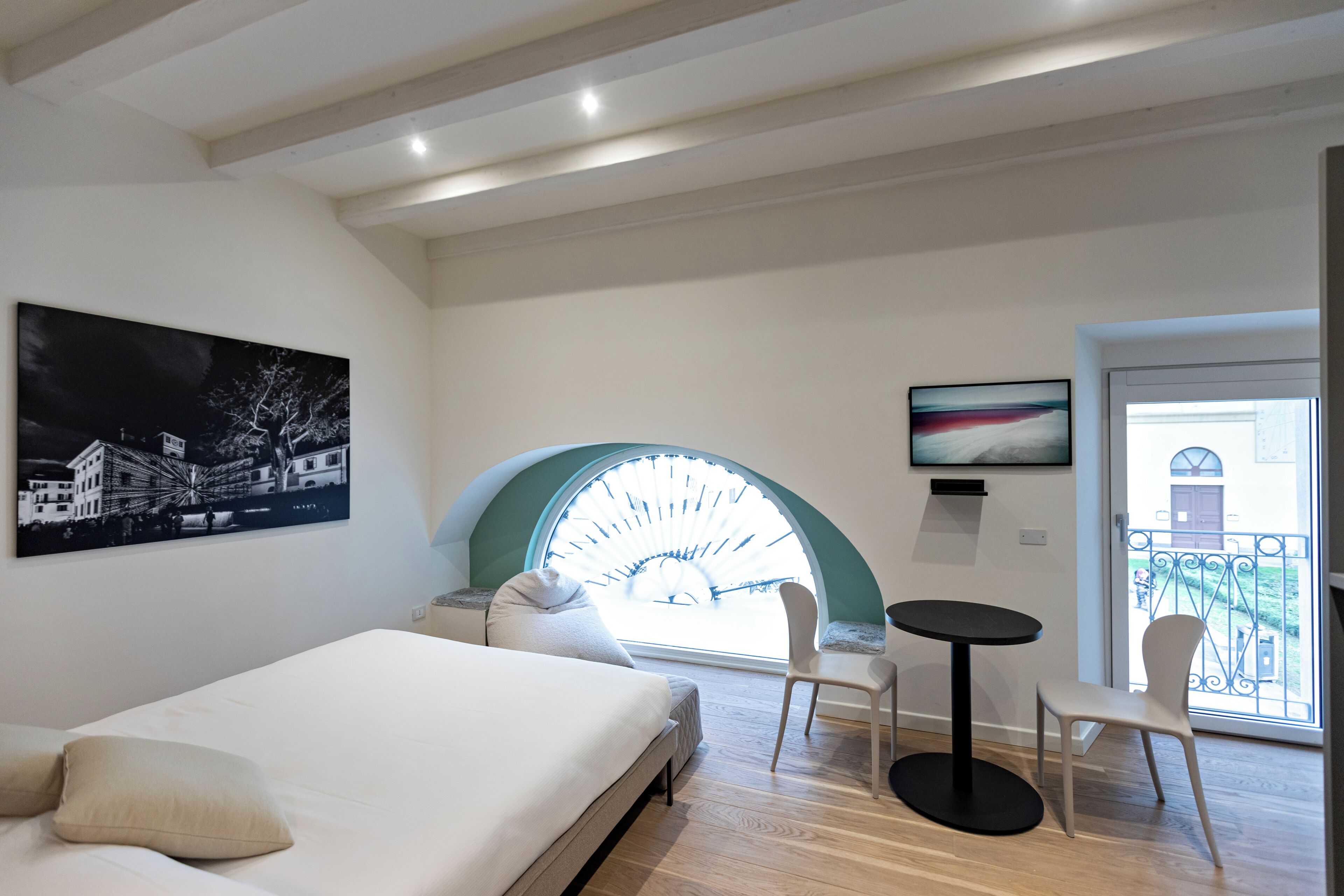 Un dormitorio moderno con cama, ventanal redondo y balcón con vistas.