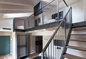A multi-level interior with a staircase, a kitchen area, and a door. - Palazzo7 (DOMODOSSOLA)