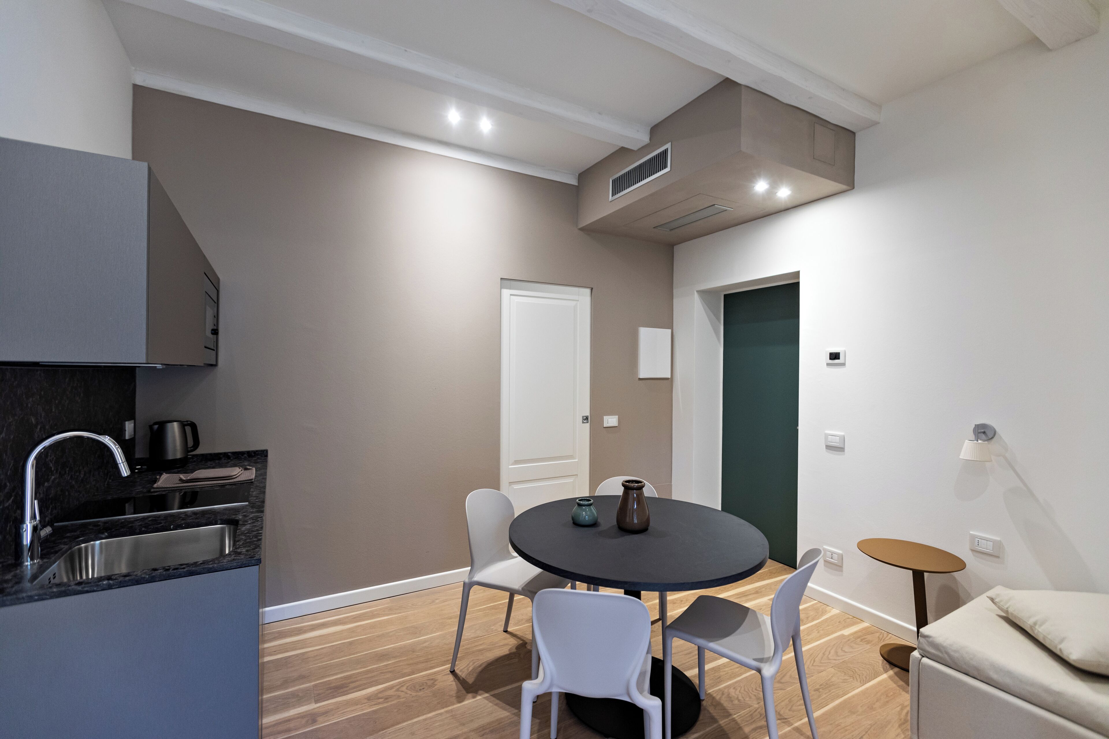 A modern kitchen with a sink, a dining table with chairs, and a small side table.