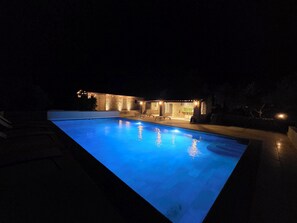 A swimming pool with a stone deck and a stone building with lights in the background. - Domaine de Fanny : Heart of Provence - 14 persons (Entrecasteaux)