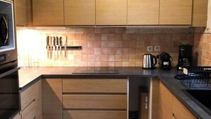 Eine moderne Küche mit Holzschränken, einer Fliesenküchenwand und einem eingebauten Geschirrspüler.