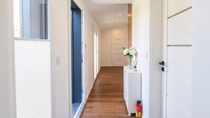 A hallway with a wooden floor, white walls, and a white door at the end. - Tinyhouse „SeeZeit“ in ruhiger, naturnaher Lage direkt am Garder See. (Lohmen)