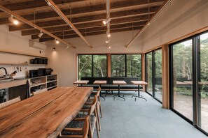 Una cocina moderna con armarios de madera, una mesa grande de madera y un área de descanso con bancos y sillas.