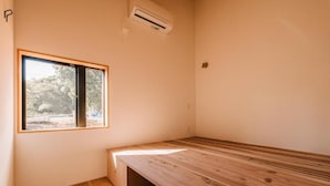 A room with a wooden bench, a window, and an air conditioning unit.