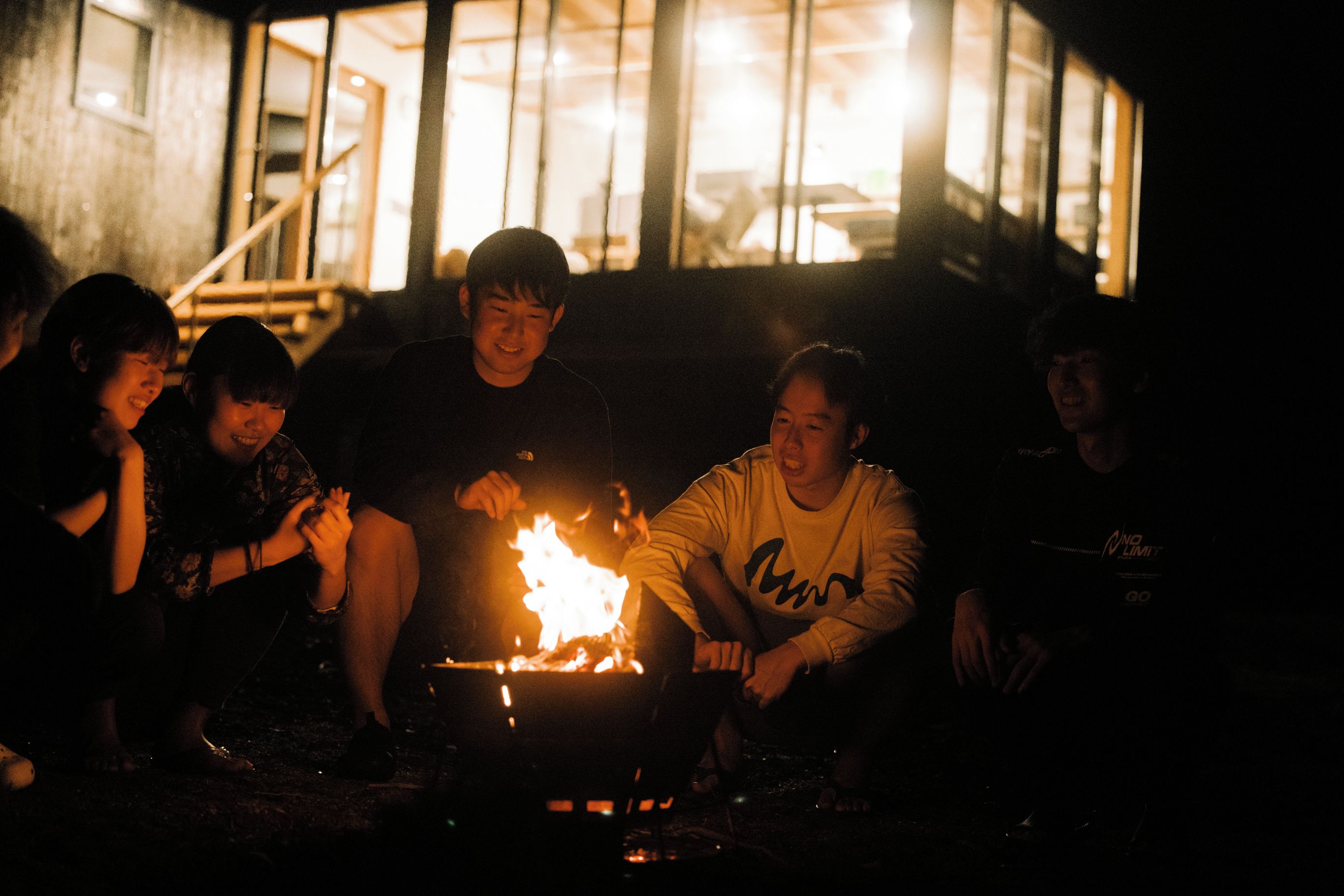 A group of people sitting around a campfire at night.