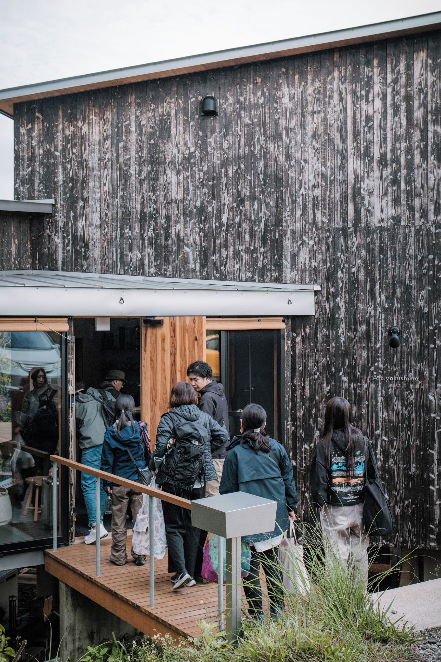 A group of people exiting a modern building with a wooden facade.