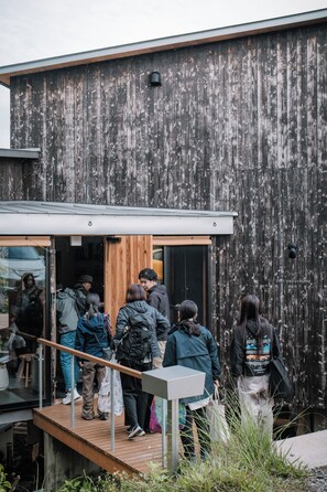 Un grupo de personas saliendo de un edificio moderno con fachada de madera.