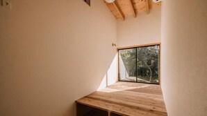 Una habitación con techo inclinado, un ventanal grande y un banco de madera.