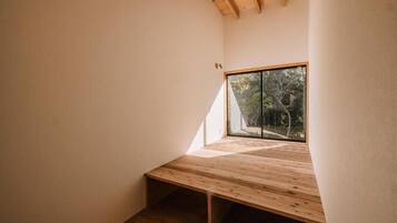 Una habitación con techo inclinado, un ventanal grande y un banco de madera.