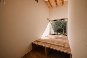 Una habitación con techo inclinado, un ventanal grande y un banco de madera.