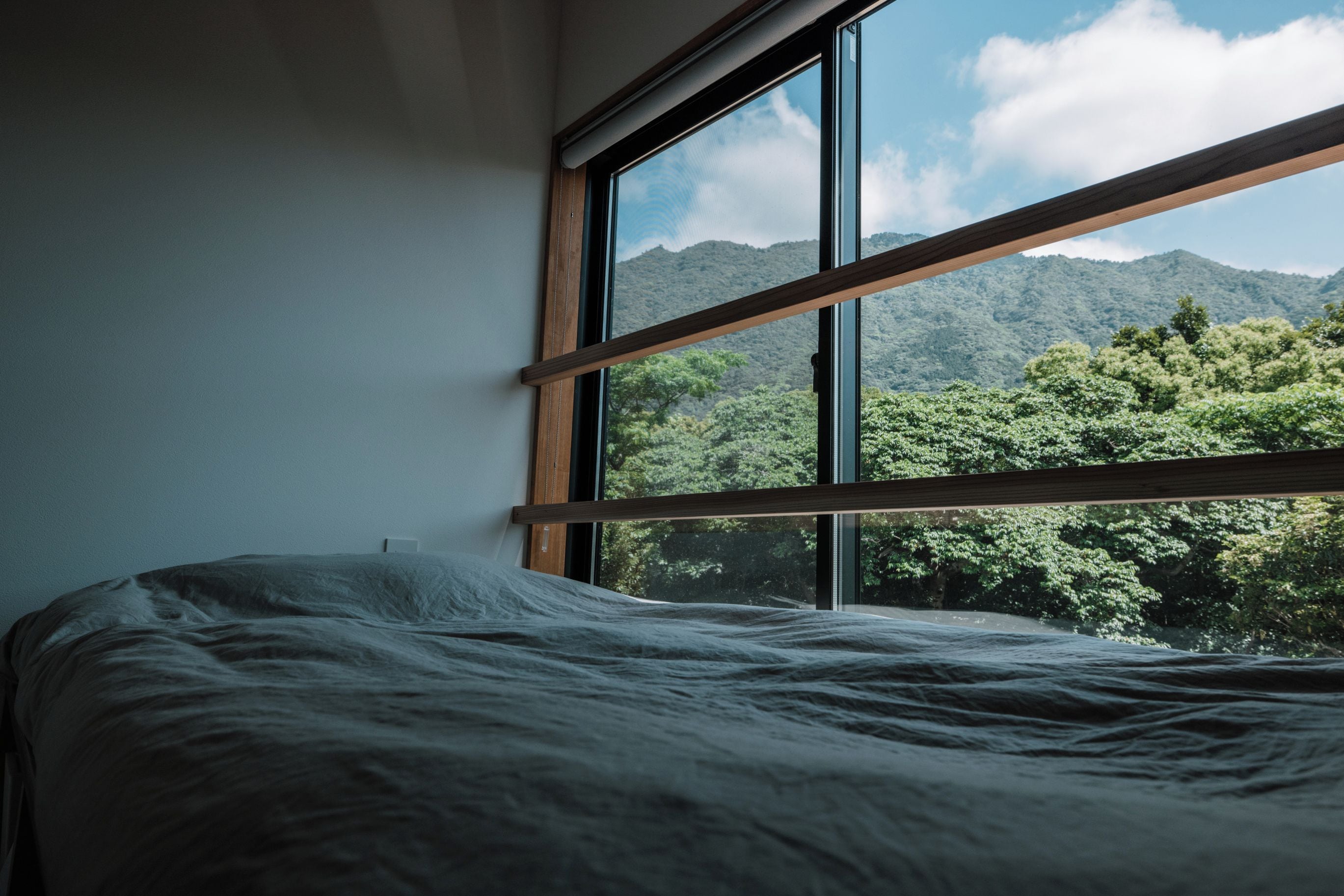 A bed in a room with a large window overlooking a mountainous landscape.