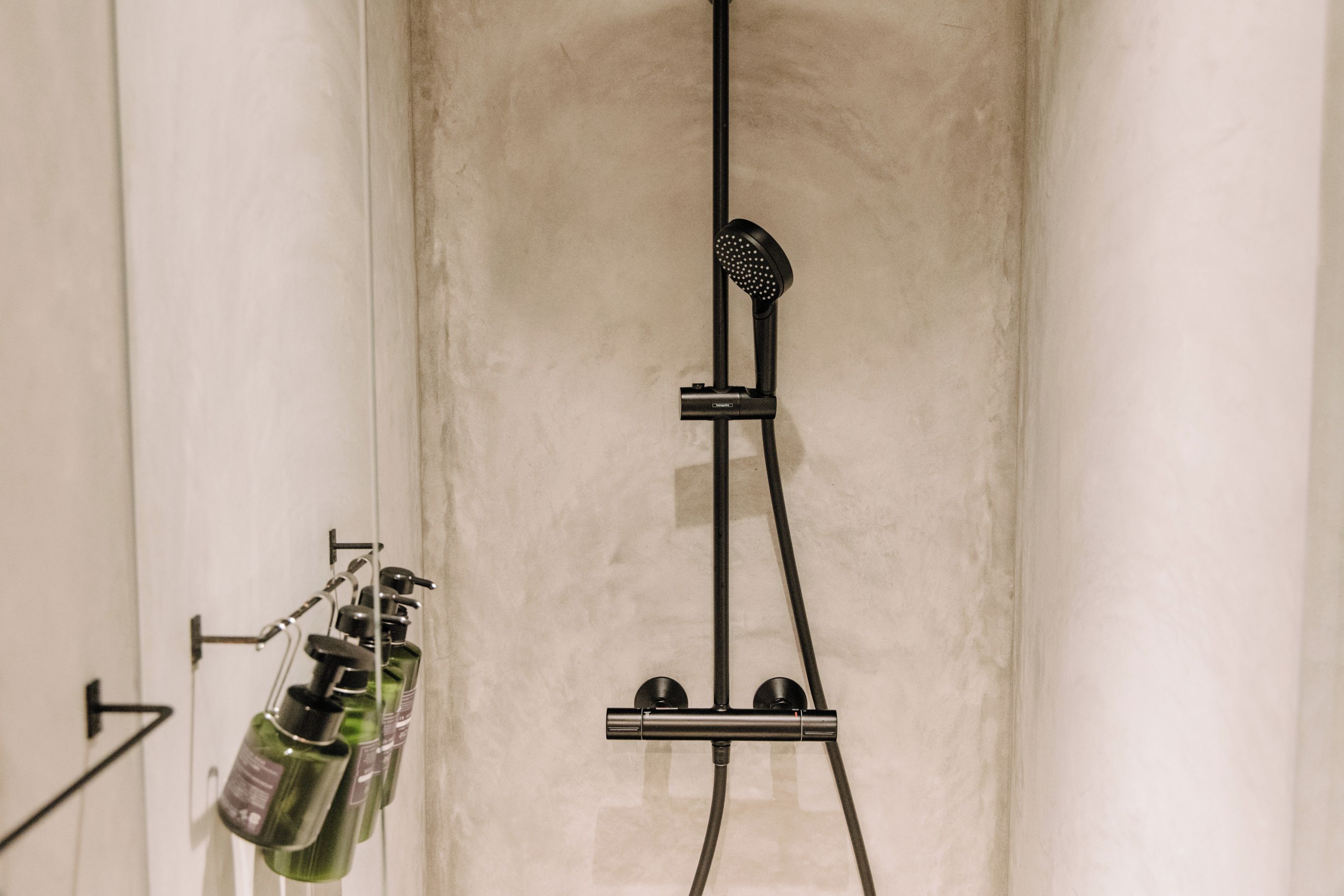Zona de ducha con ducha de mano y panel de control en la pared.