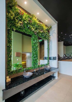 A bathroom with a mirror, two sinks, and a green vertical garden. - Corporate Stays Unico - 1405  (Asunción)